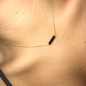 Gold chain necklace with black pendant.